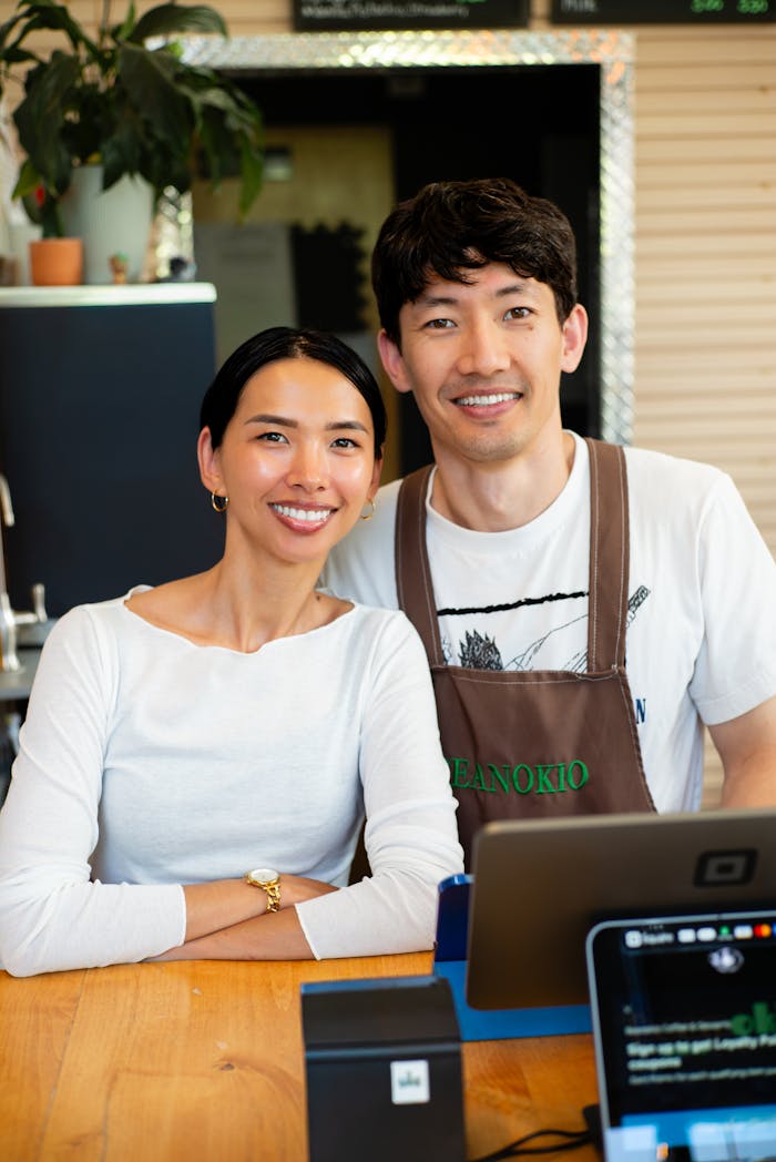 ours-journey Portrait of two smiling coffee shop owners standing behind counter. Ideal for business and small enterprise themes.
