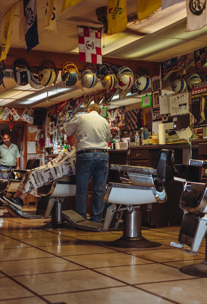 services-02 A cozy vintage barbershop with a barber attending to a client amidst retro decor and helmets.